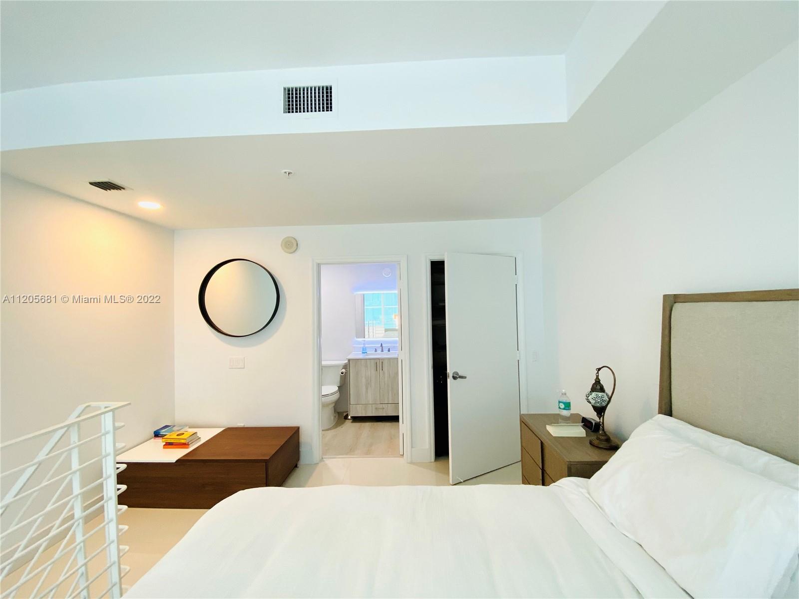 60 Southwest 13th Street, Unit 1412 Miami, FL 33130 - Photo 22 of 39 a bedroom with bed and a chandelier