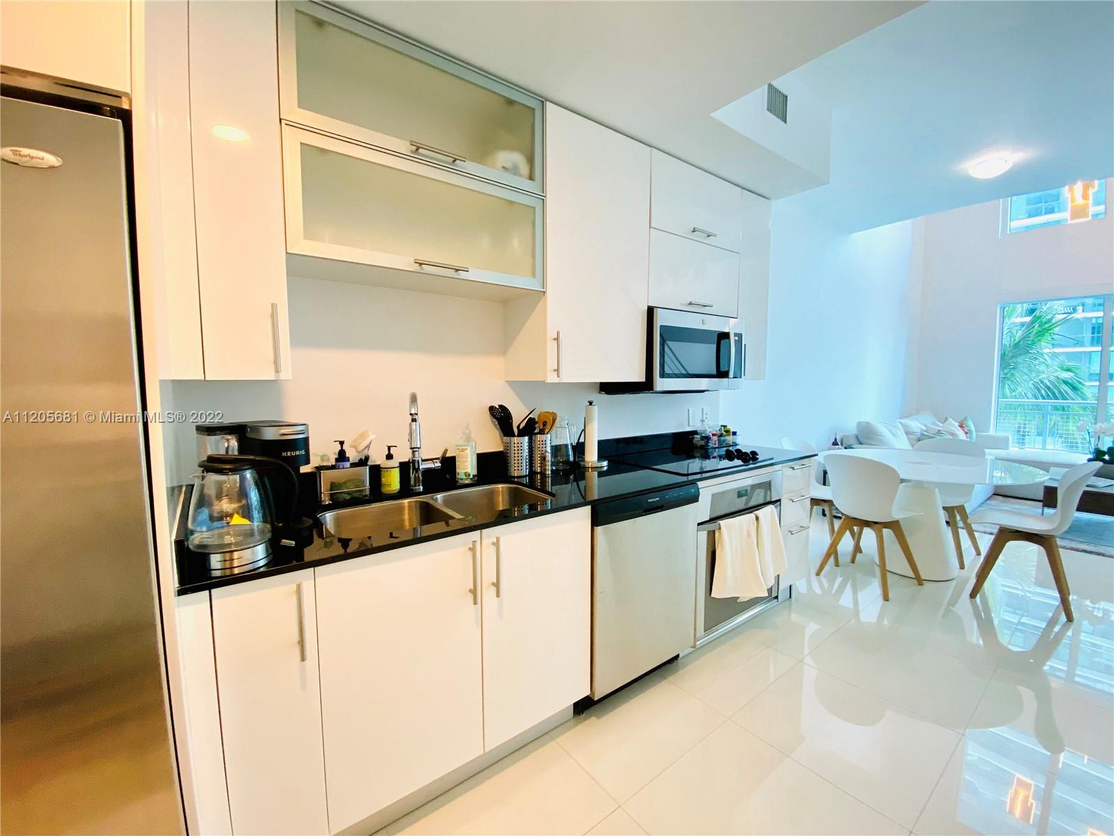 60 Southwest 13th Street, Unit 1412 Miami, FL 33130 - Photo 3 of 39 a kitchen with white cabinets and chairs