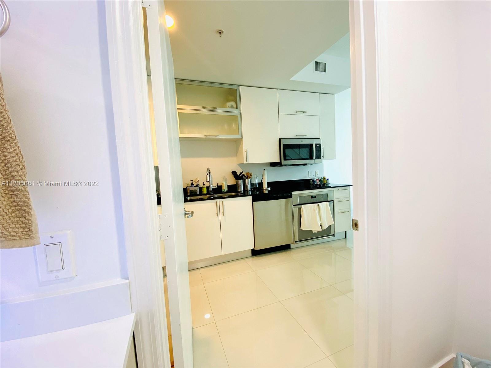 60 Southwest 13th Street, Unit 1412 Miami, FL 33130 - Photo 5 of 39 a kitchen with stainless steel appliances a sink and a refrigerator