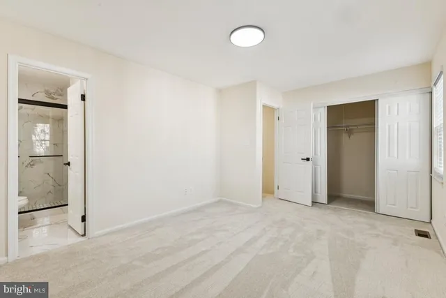 a view of an empty room with wooden floor and a bathroom