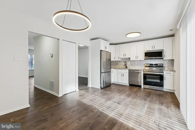 a kitchen with stainless steel appliances a refrigerator cabinets and wooden floor