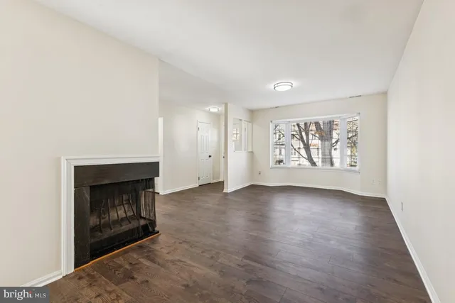 an empty room with windows and fireplace