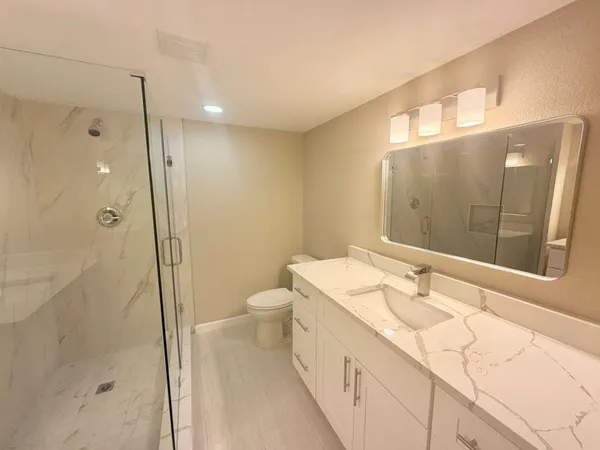 a bathroom with a sink a toilet and shower