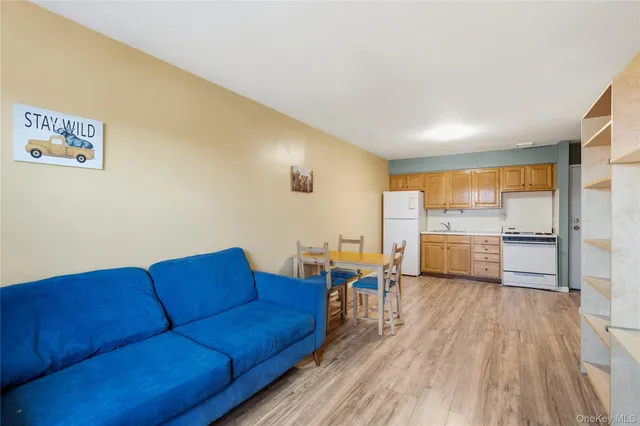 a living room with couches chairs and kitchen view with wooden floor