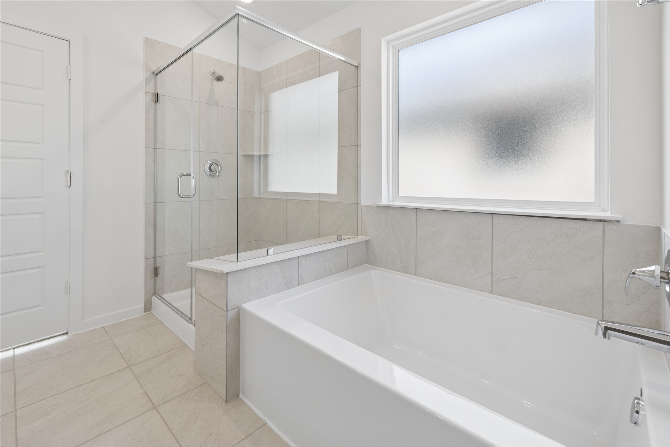1697 Hopson Ranch Drive Conroe, TX 77301 - Photo 15 of 26 Bright and modern bathroom featuring a spacious glass-enclosed shower and a sleek, inviting bathtub, complemented by elegant tilework and abundant natural light.