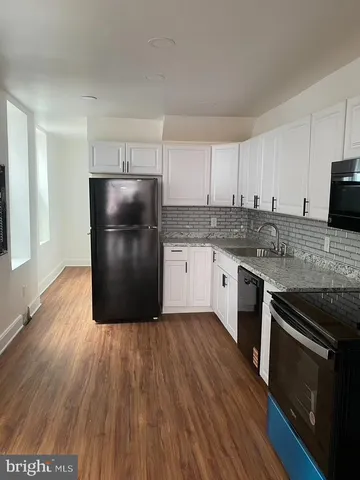 a kitchen with kitchen island granite countertop a sink cabinets and stainless steel appliances