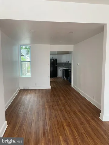 an empty room with wooden floor fireplace and windows