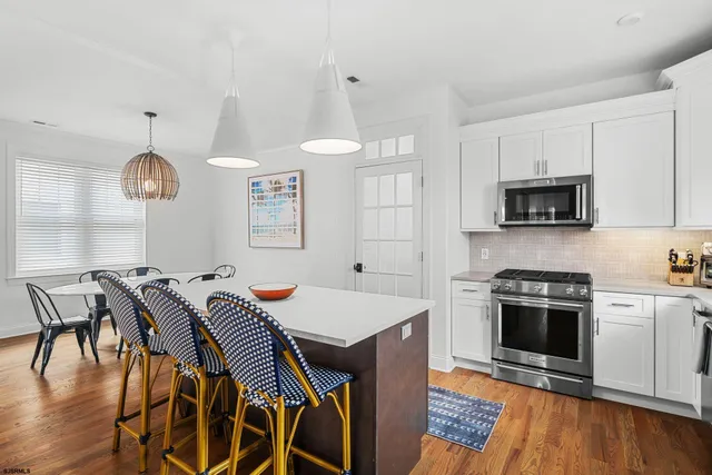 a kitchen with stainless steel appliances a stove a sink microwave and a dining table with wooden floor