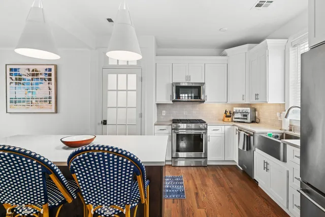 a kitchen with stainless steel appliances a stove a sink cabinets and a wooden floor