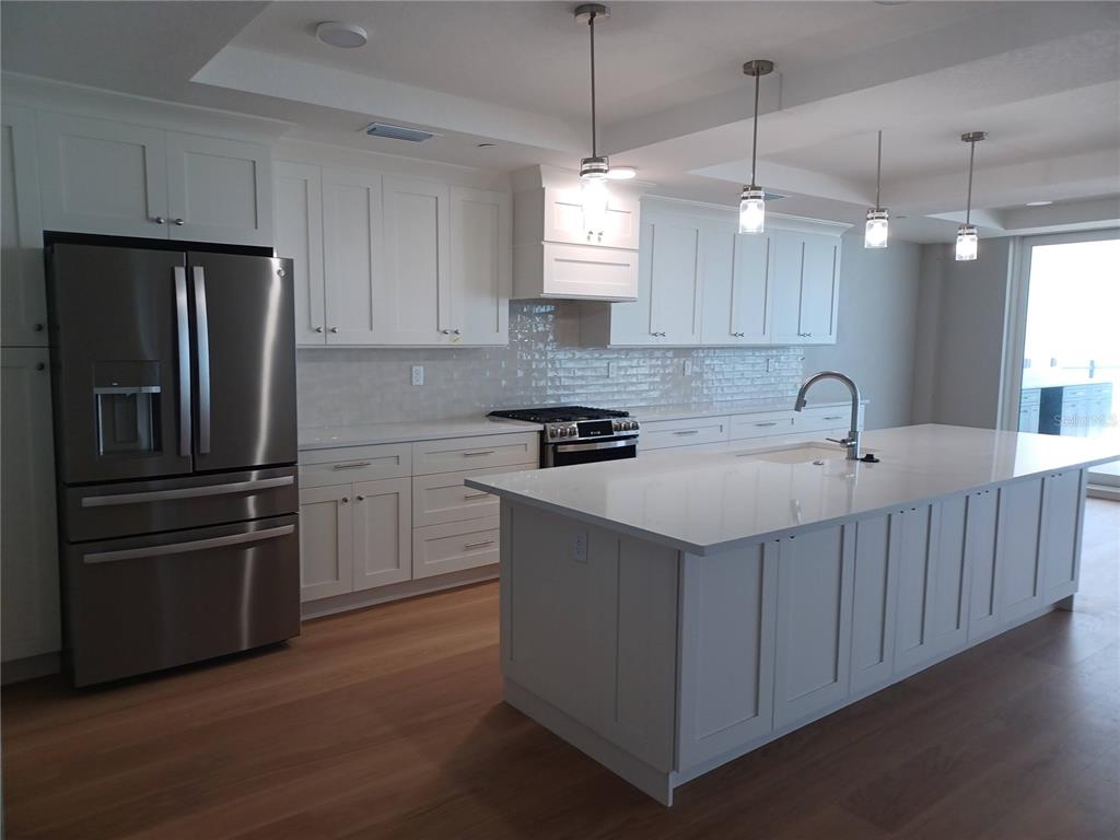14048 Gulf Boulevard, Unit 401 Madeira Beach, FL 33708 - Photo 4 of 14 a kitchen with stainless steel appliances granite countertop a sink stove a refrigerator and a center island