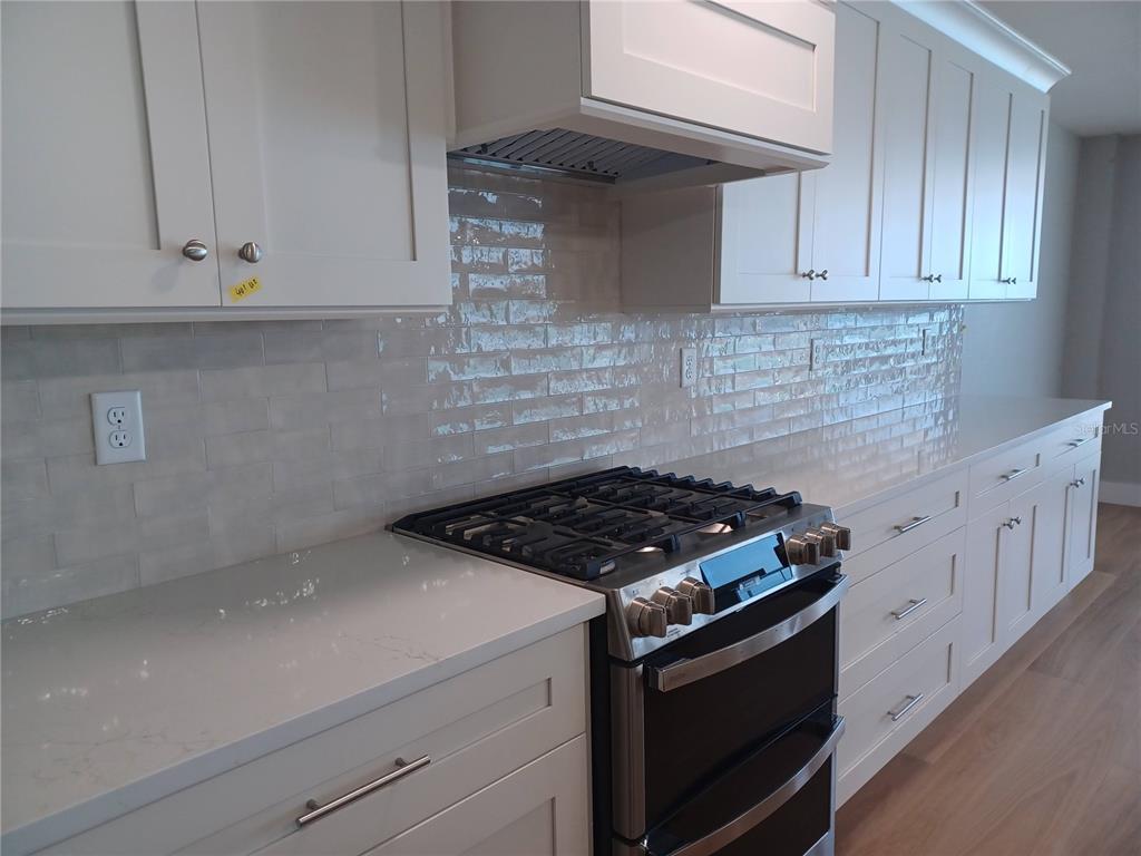 14048 Gulf Boulevard, Unit 401 Madeira Beach, FL 33708 - Photo 5 of 14 a kitchen with granite countertop white cabinets and stainless steel appliances