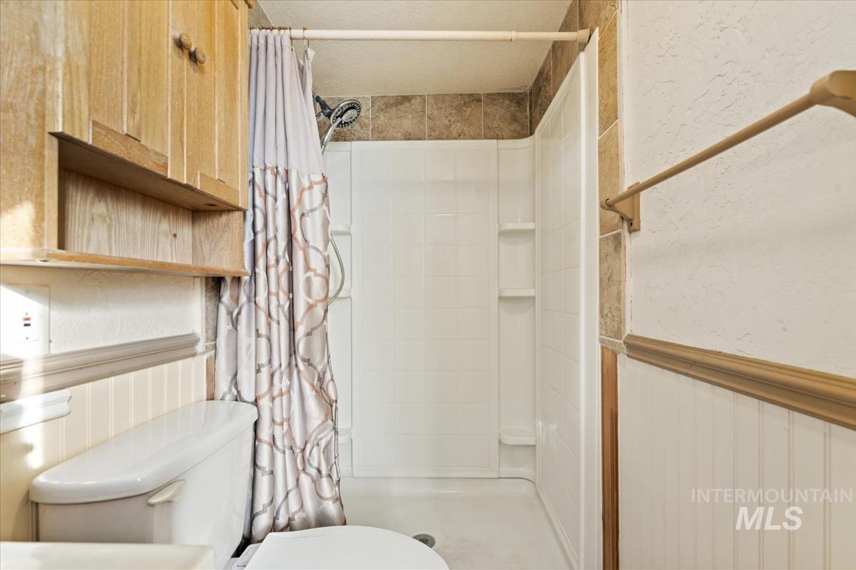 351 East 3rd Street Kuna, ID 83634 - Photo 13 of 42 Full bathroom with a wainscoted wall and a shower stall