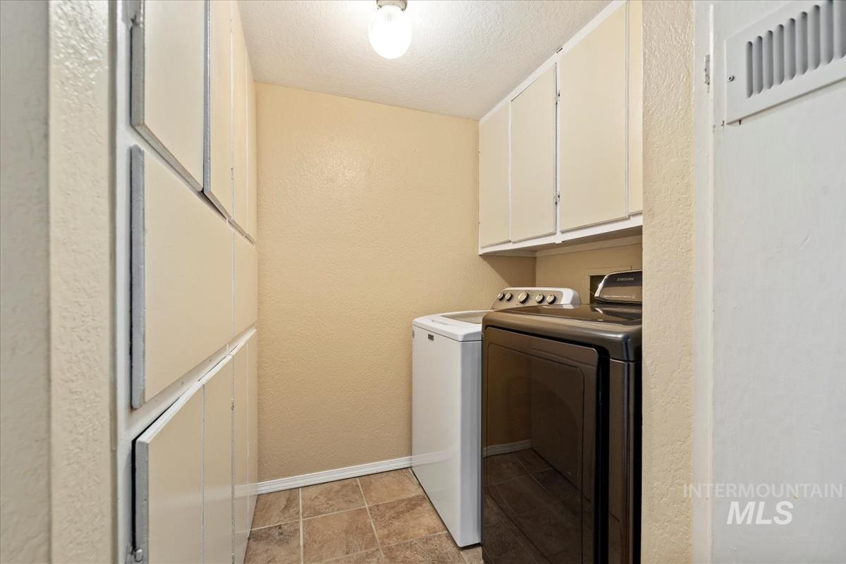 351 East 3rd Street Kuna, ID 83634 - Photo 14 of 42 Laundry area with a textured wall, a textured ceiling, separate washer and dryer, and cabinet space