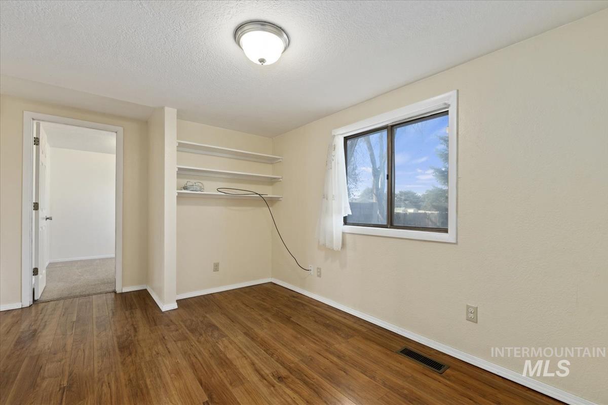 351 East 3rd Street Kuna, ID 83634 - Photo 15 of 42 Unfurnished bedroom featuring dark wood-style flooring and a textured ceiling