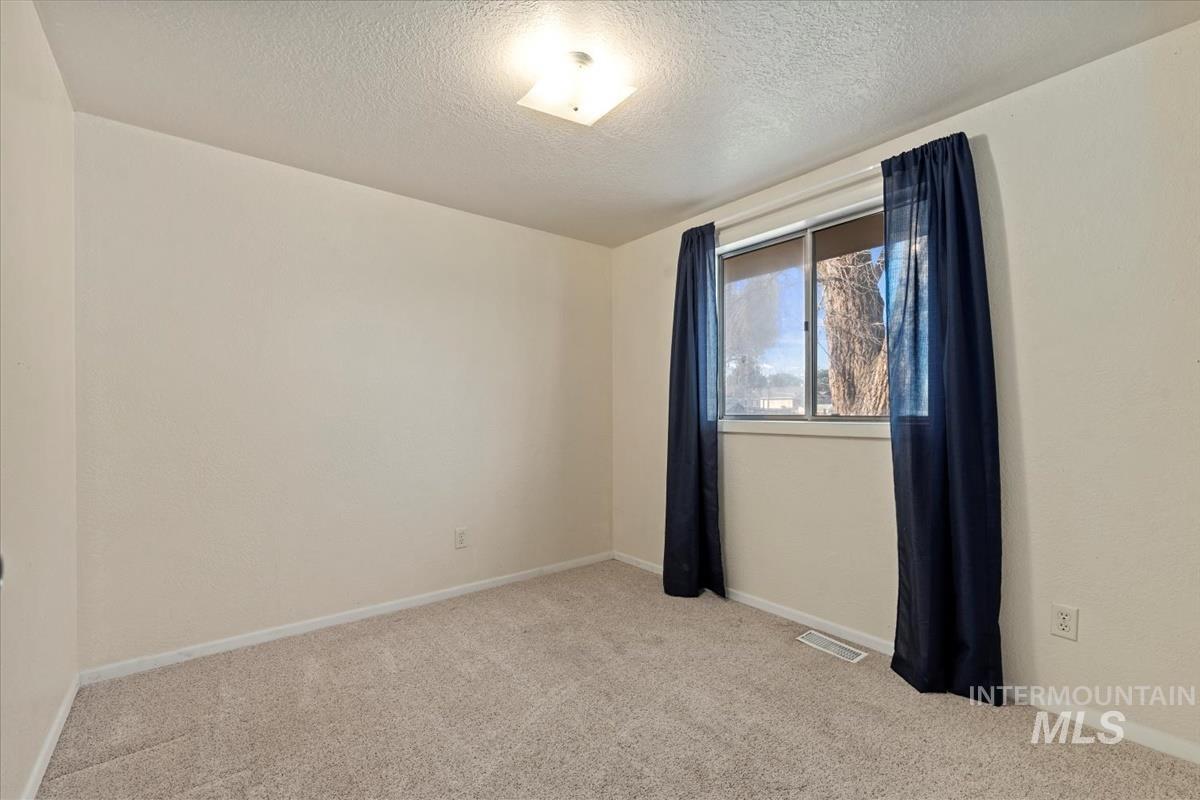 351 East 3rd Street Kuna, ID 83634 - Photo 16 of 42 Empty room featuring light colored carpet and a textured ceiling