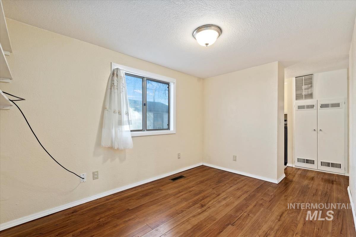 351 East 3rd Street Kuna, ID 83634 - Photo 23 of 42 Spare room with dark wood finished floors, a textured ceiling, and a heating unit