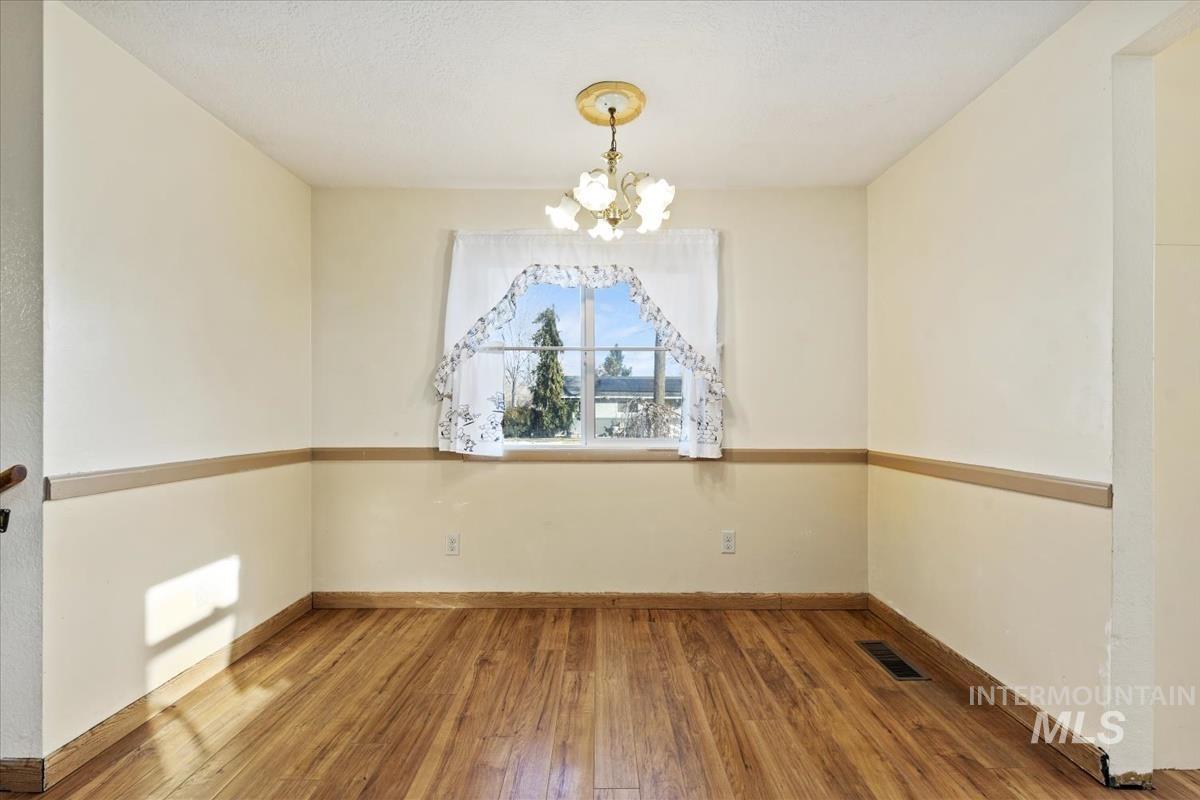 351 East 3rd Street Kuna, ID 83634 - Photo 24 of 42 Unfurnished room featuring hardwood / wood-style flooring and hanging lights