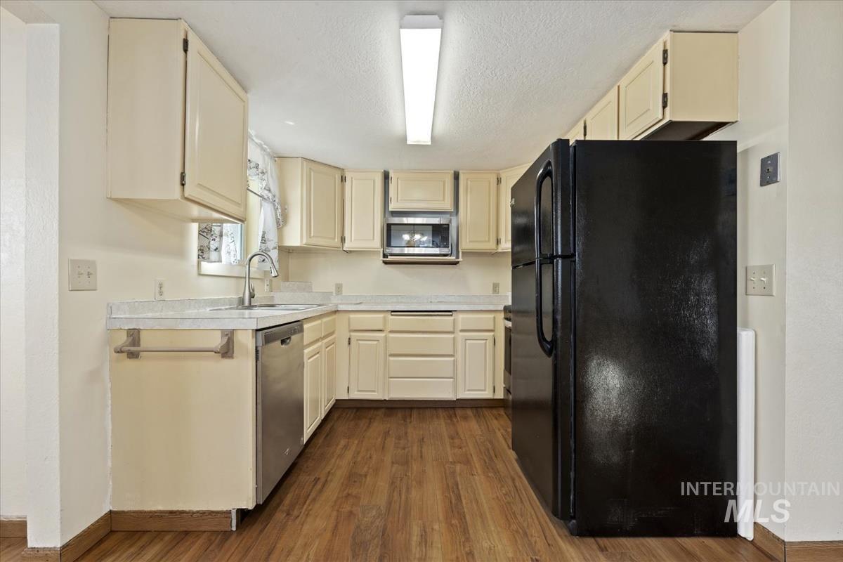 351 East 3rd Street Kuna, ID 83634 - Photo 6 of 42 Kitchen featuring stainless steel appliances, light countertops, dark wood-style floors, cream cabinetry, and a textured ceiling
