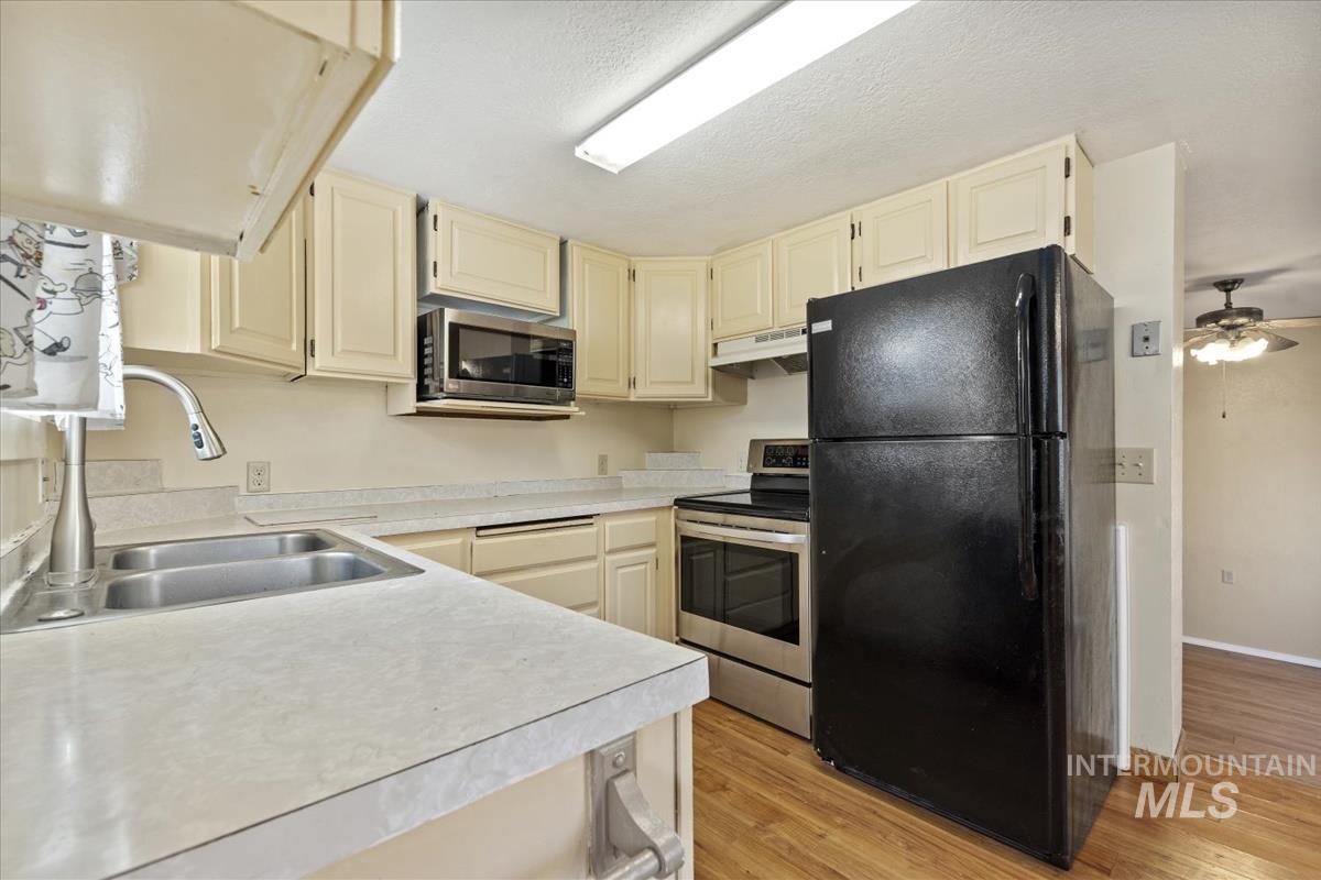351 East 3rd Street Kuna, ID 83634 - Photo 7 of 42 Kitchen with stainless steel appliances, cream cabinets, light countertops, light wood-style flooring, and a textured ceiling