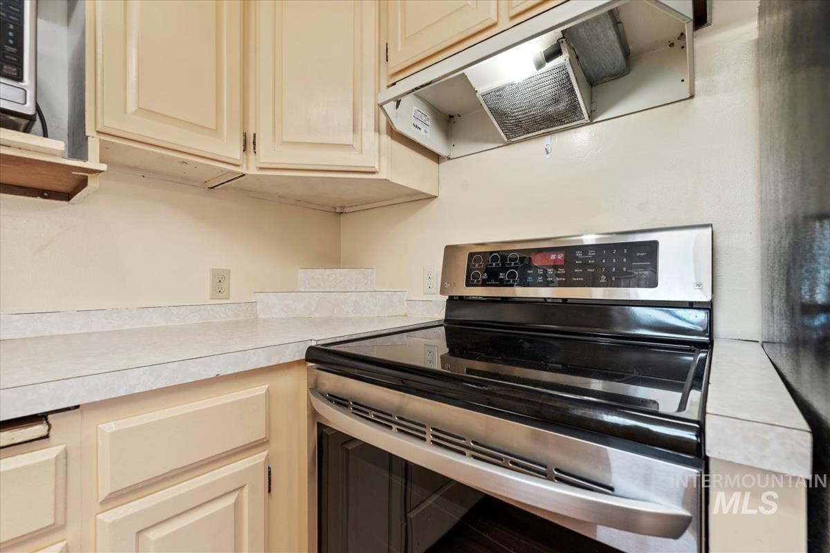 351 East 3rd Street Kuna, ID 83634 - Photo 8 of 42 Kitchen featuring stainless steel electric stove, light countertops, exhaust hood, and cream cabinets