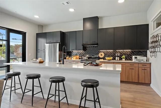 a kitchen with stainless steel appliances kitchen island granite countertop a stove a sink and a refrigerator