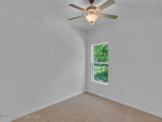 an empty room with a window and a fan