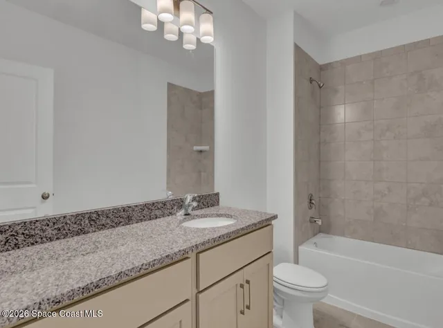 a bathroom with a granite countertop sink a toilet a mirror a bathtub and shower