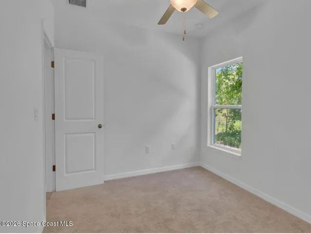 an empty room with a window and a fan