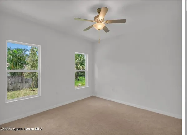 an empty room with windows and fan