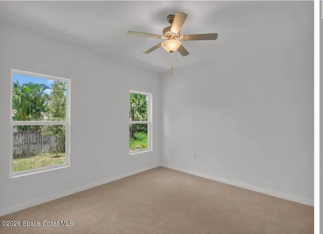an empty room with windows and fan