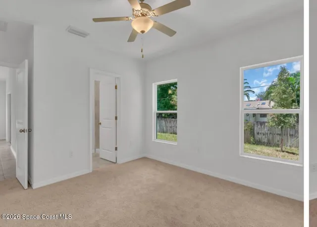 an empty room with a window and a fan