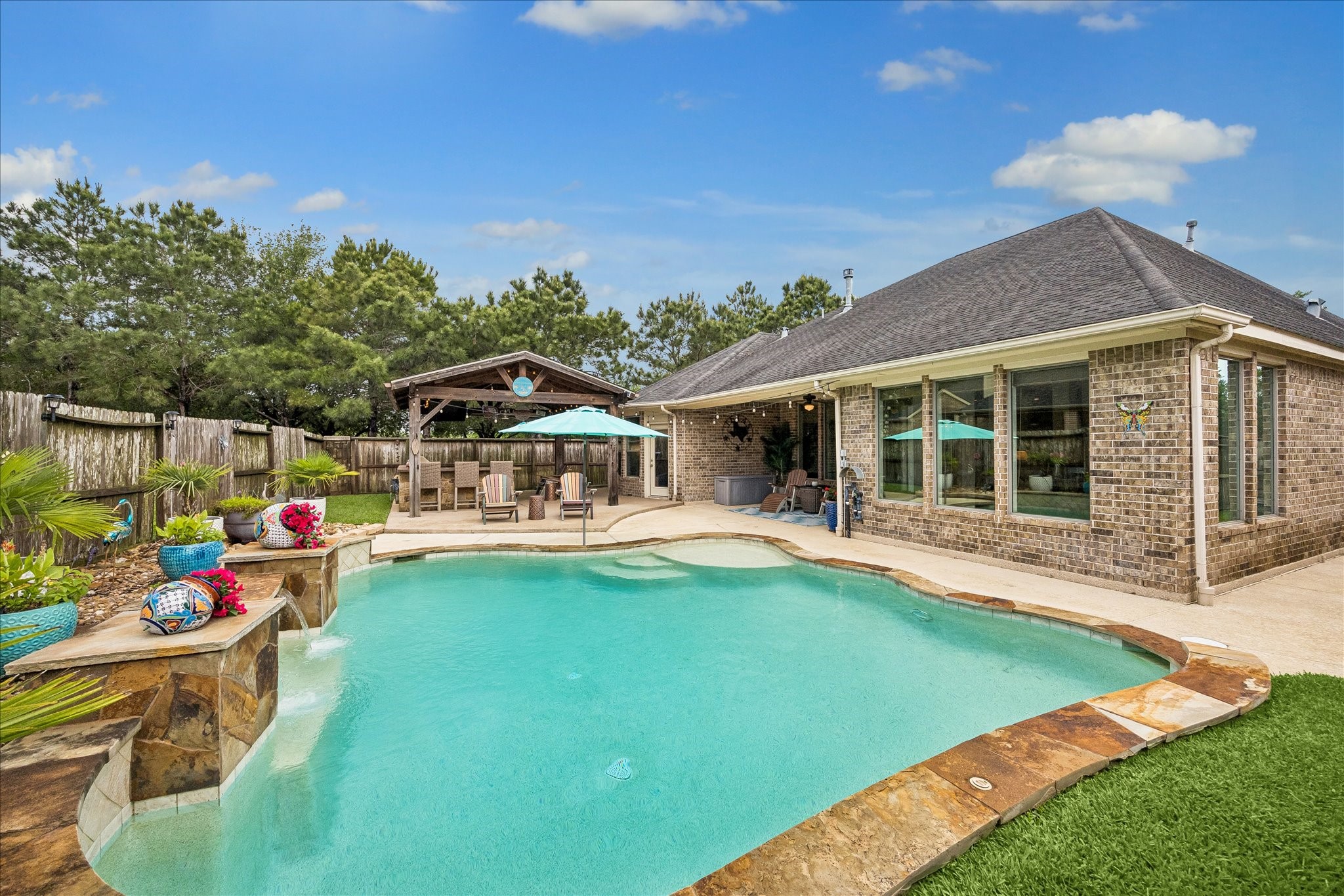 28211 Rippling Brook Lane Fulshear, TX 77441 - Photo 28 of 45 RESORT-STYLE POOL: Pebble-tec pool with tanning ledge and multiple water features creates a stunning focal point for outdoor living and entertaining.