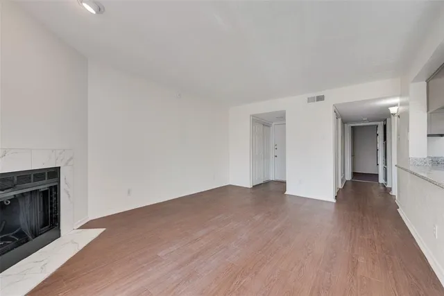 a view of an empty room with wooden floor and a fireplace