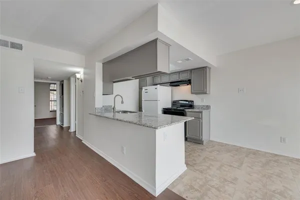 a kitchen with white cabinets and a stove with wooden floor