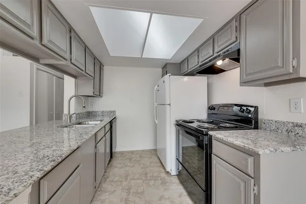 a kitchen with granite countertop a sink stove and refrigerator