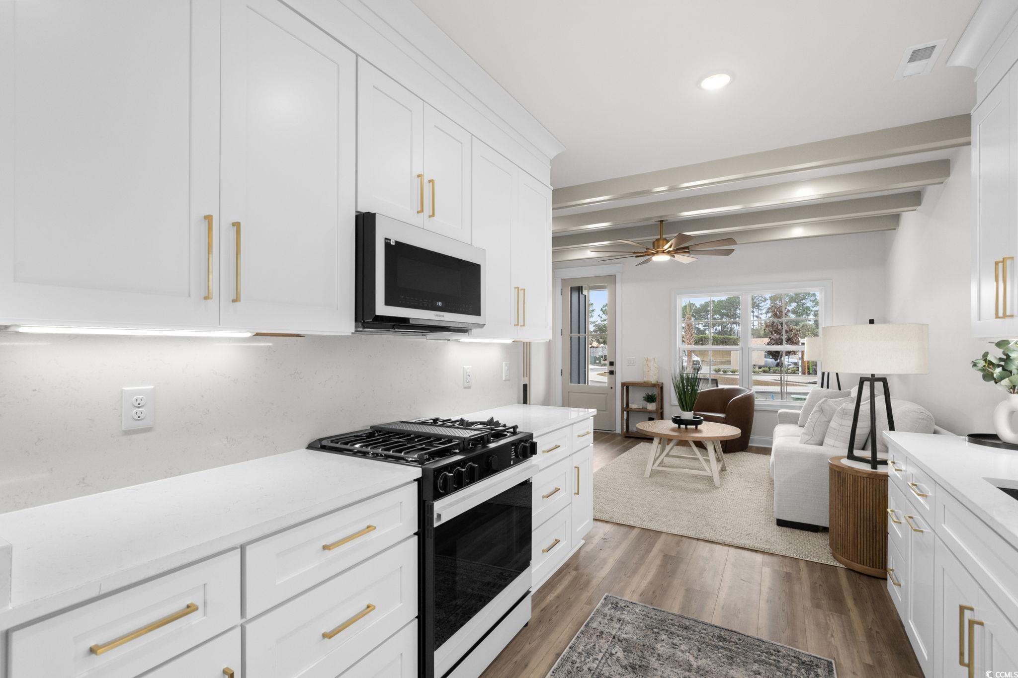 156 Arbor Ridge Circle Conway, SC 29526 - Photo 11 of 40 Kitchen featuring black gas range oven, white cabinetry, white microwave, beam ceiling, and light wood-style flooring
