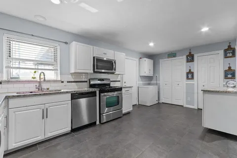 a kitchen with white cabinets and white appliances