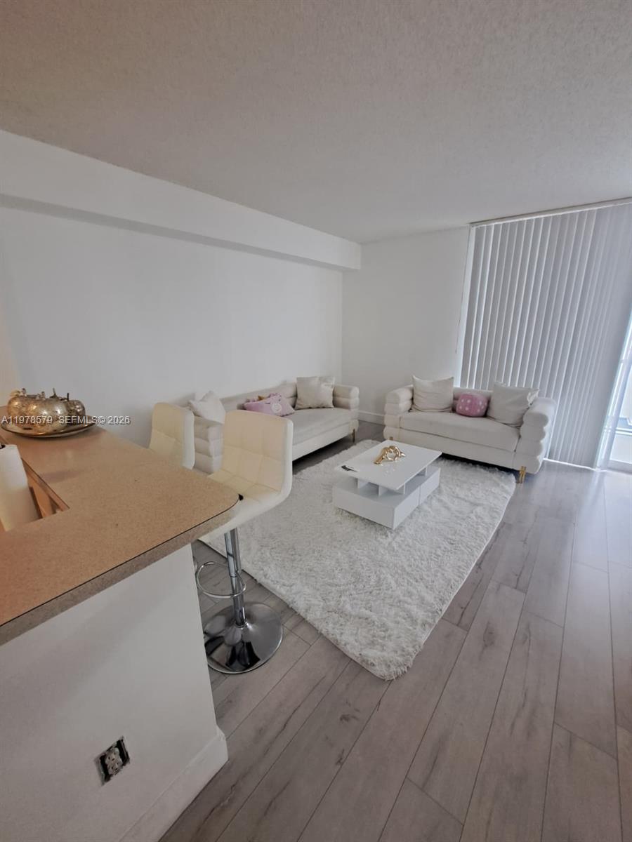 5077 Northwest 7th Street, Unit 912 Miami, FL 33126 - Photo 2 of 28 a living room with furniture and a wooden floor
