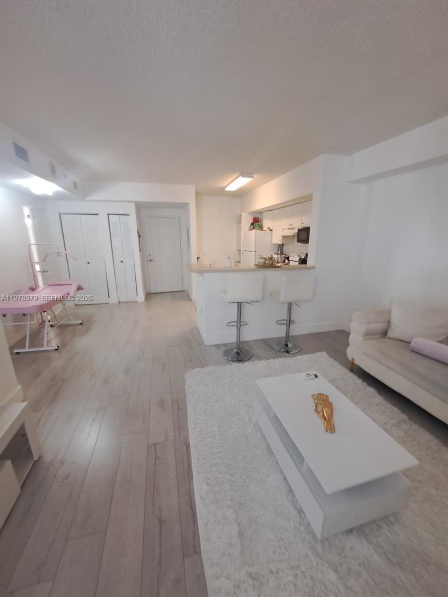 5077 Northwest 7th Street, Unit 912 Miami, FL 33126 - Photo 5 of 28 a large white kitchen with wooden floors and a sink