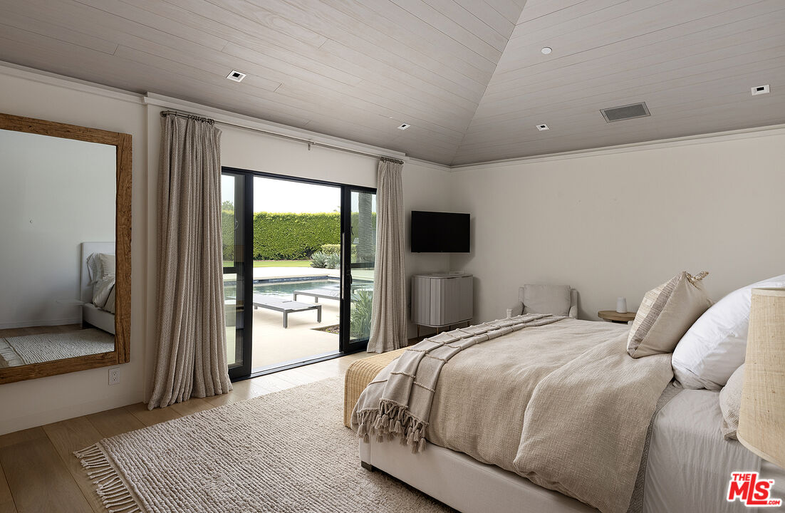 4145 Creciente Drive Santa Barbara, CA 93110 - Photo 31 of 57 a bedroom with a large bed and a flat tv screen next to a large window