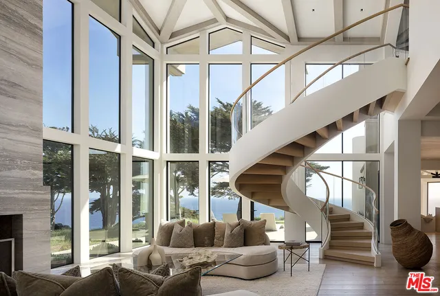 a living room with furniture a fireplace and a large window