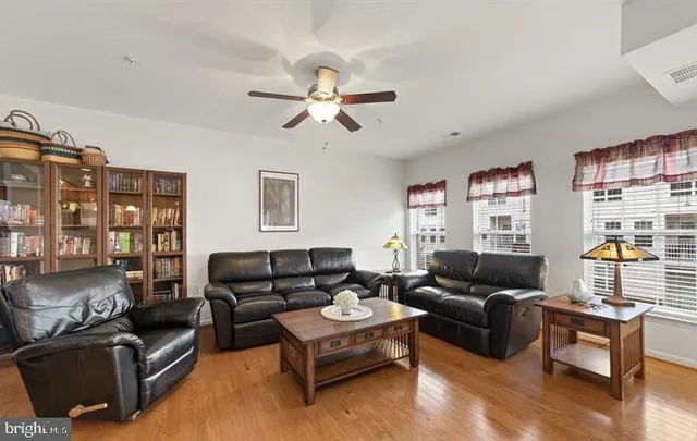 a living room with couches chandelier and wooden floor