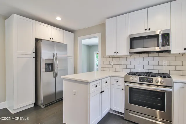 a kitchen with white cabinets and stainless steel appliances