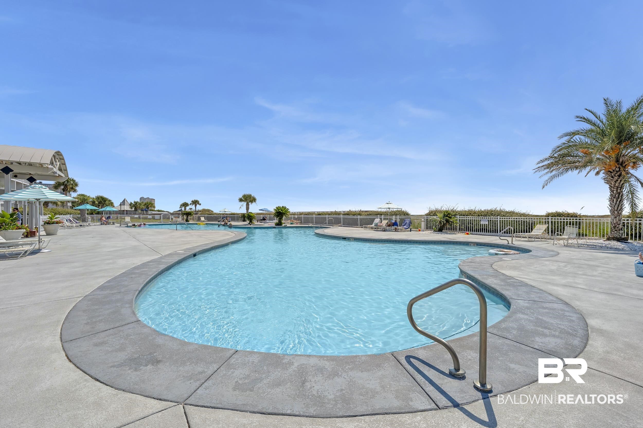 400 Plantation Road, Unit 2118 Gulf Shores, AL 36542 - Photo 28 of 59 Expansive outdoor pool with an organic shape, surrounded by a concrete deck and a white metal fence