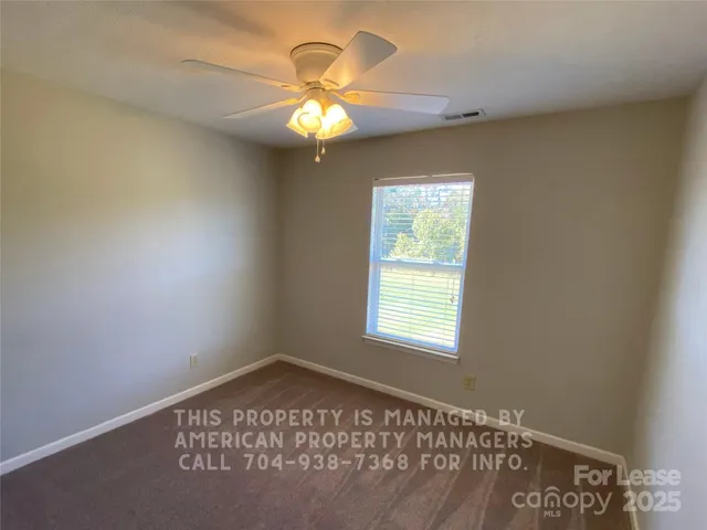 an empty room with a chandelier fan