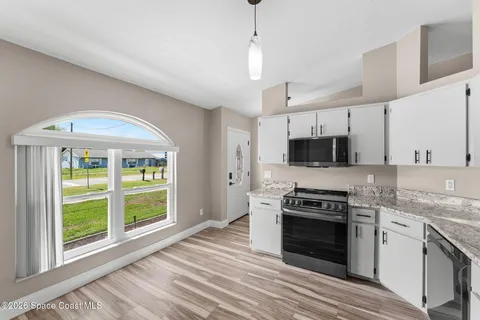 a kitchen with stainless steel appliances granite countertop a stove a sink and a microwave