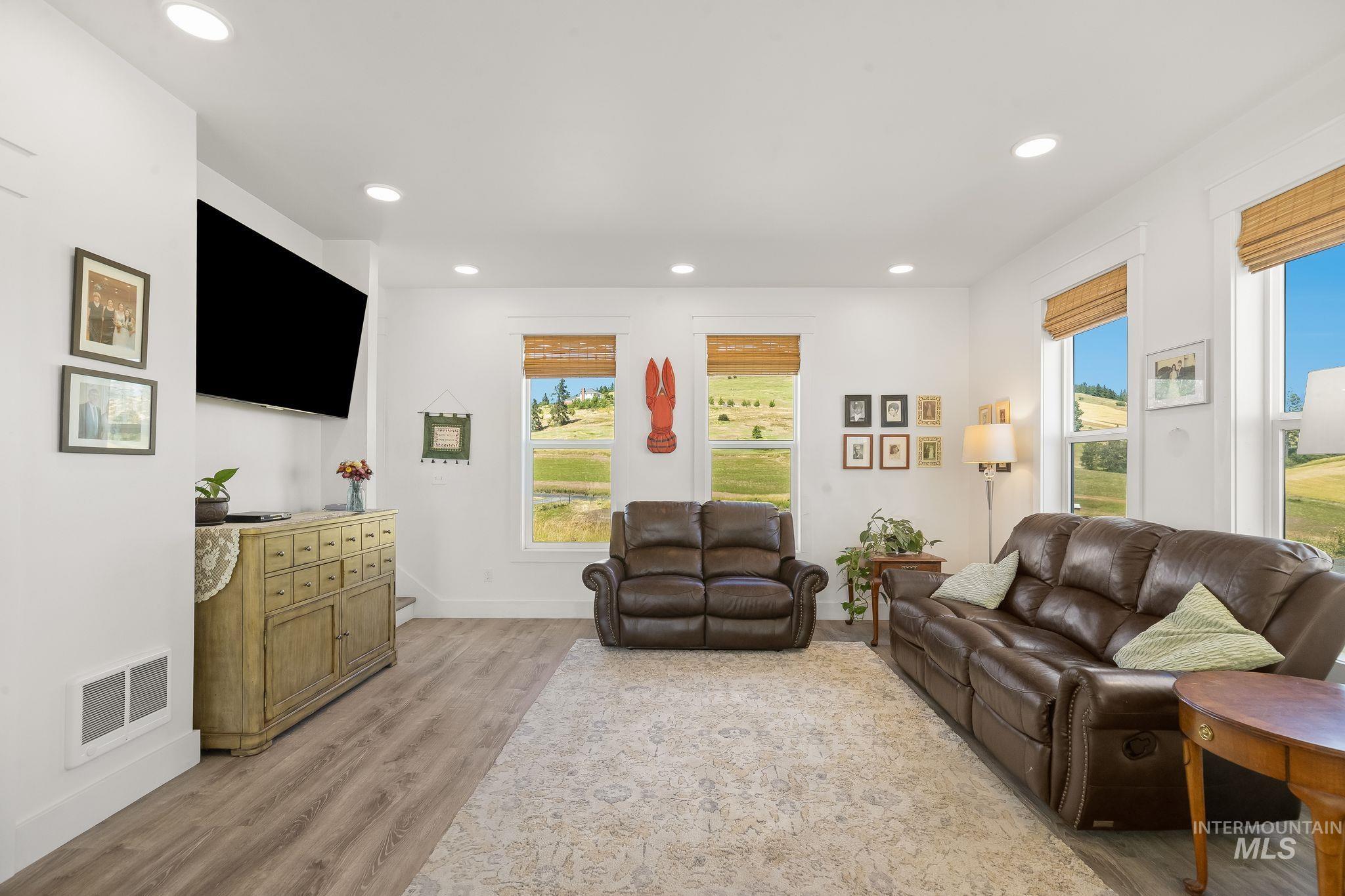 4935 Lenville Road Moscow, ID 83843 - Photo 11 of 49 Living area featuring wood-finish flooring, white walls, and multiple windows with bamboo-style shades