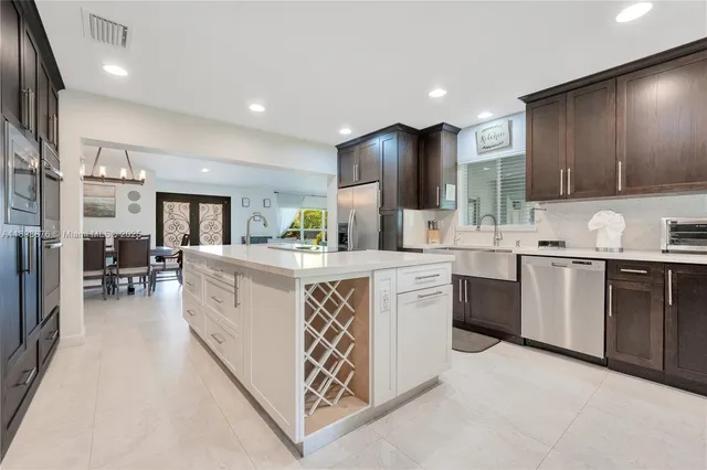 a kitchen with stainless steel appliances granite countertop a stove top oven a sink dishwasher a refrigerator and white cabinets with wooden floor