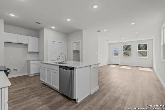 a kitchen with stainless steel appliances granite countertop a sink and wooden floors