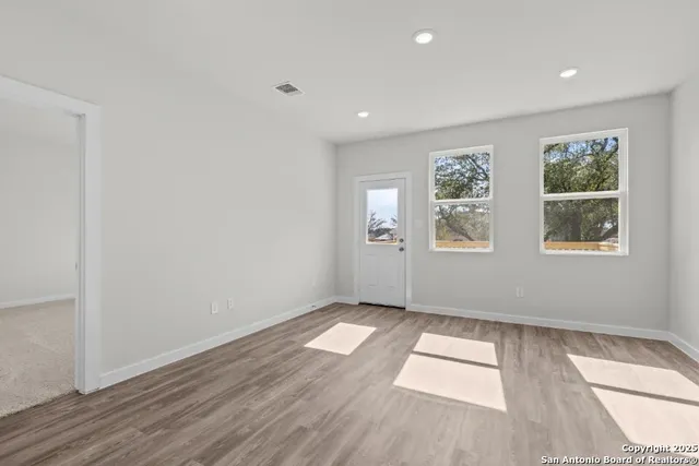 an empty room with wooden floor and windows